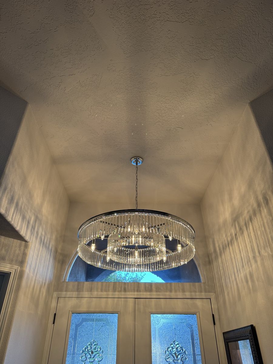 Round crystal chandelier lighting a tall entryway
