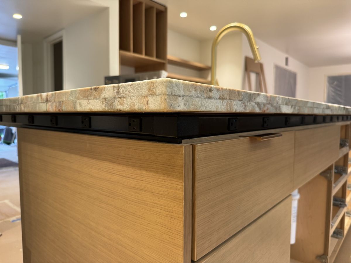 Black plug mold outlet strip installed under a kitchen island countertop